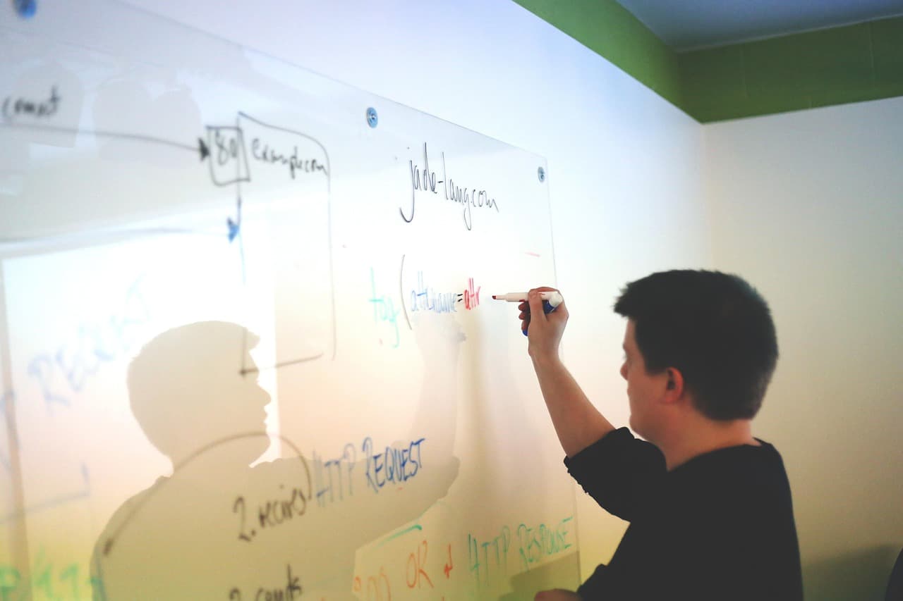 Drawing a flowchart with boxes and arrows on a whiteboard