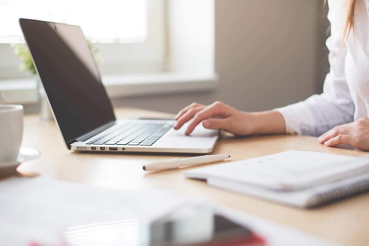 Hands working on a laptop in a bright, clean office