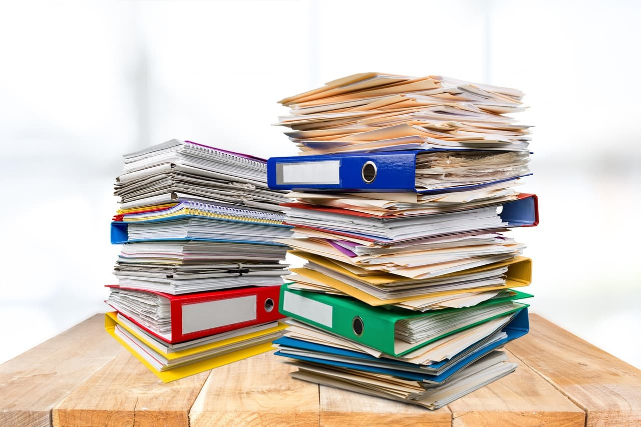 Stacks of binders and paperwork piled on a desk